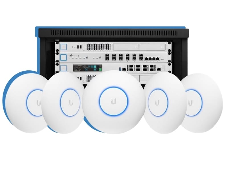 Produktabbildung von professionellen Ubiquiti UniFi Netzwerkkomponenten, bei der vier flache, runde WLAN-Access-Points mit blau leuchtendem LED-Ring vor einem voll ausgestatteten 19-Zoll-Netzwerkschrank angeordnet sind. Diese aufeinander abgestimmte Hardware wird von syskypo installiert, um durch verlässlichen Netzwerkschutz und die Trennung von internen Daten und Gäste-WLAN die IT-Sicherheit in Ihrem Betrieb zu maximieren.