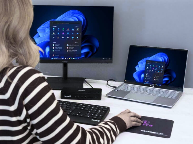 Eine Mitarbeiterin an einem modern eingerichteten Büroarbeitsplatz mit Tastatur vor einem Terra-Monitor und Terra-Laptop von der Wortmann AG. Diese langlebigen Computersysteme werden von syskypo für eine ausfallsichere IT-Betreuung ausgewählt, fachgerecht eingerichtet und betriebsbereit übergeben.